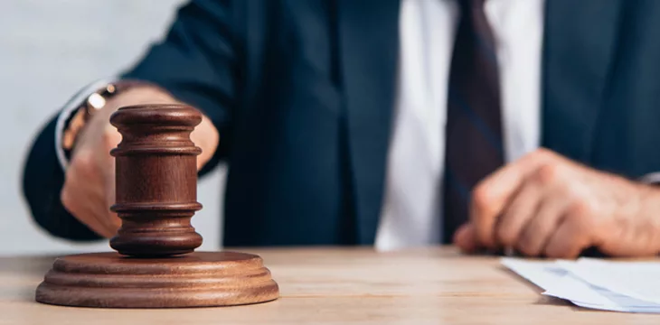 Horizontal crop of man holding gavel near papers on table