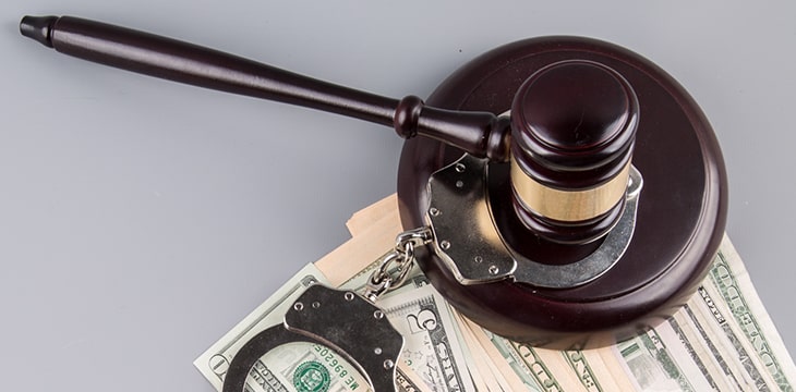 Top view of a gavel on top of a handcuff and some US Dollar bills