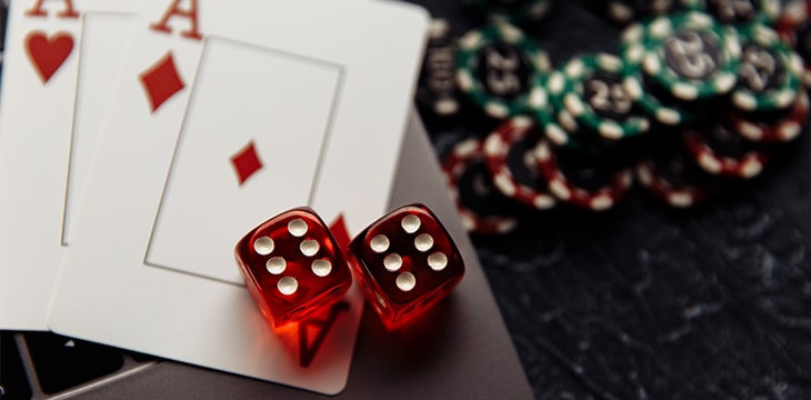 Gambling chips and five red dices on laptop keyboard close-up