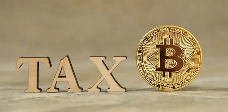 Bitcoin and wooden letters TAX on stone background