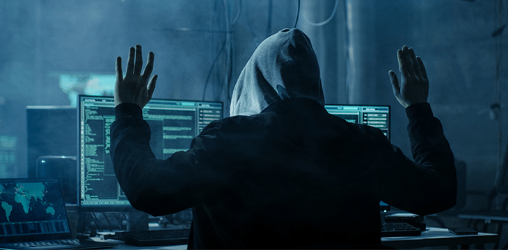 A man wearing a hood in front of computer