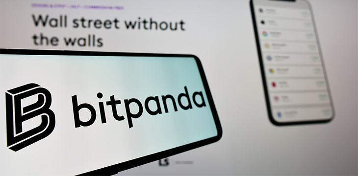 Mobile phone with logo of Austrian crypto exchange company Bitpanda GmbH on screen in front of business website. Focus on left of phone display