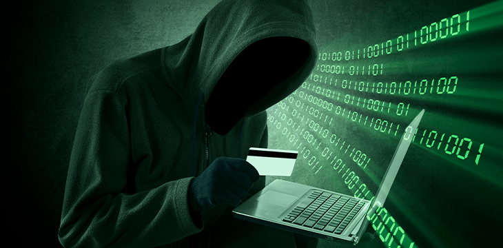 Mysterious man in a hoodie with computer and card