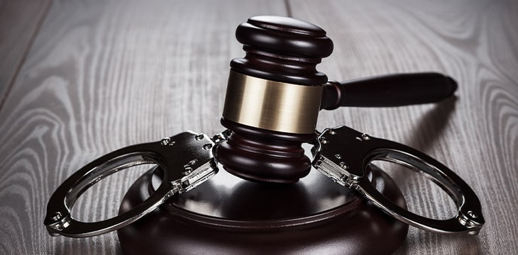 Handcuffs and judge gavel on brown table