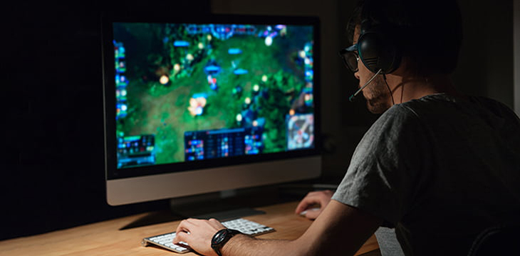 Concentrated gamer in headphones using computer for playing game.