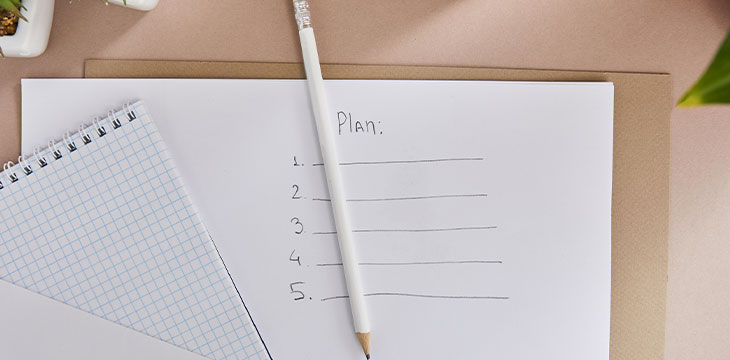 Top view of green plants, envelope, blank notebook, and a pencil