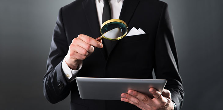 Businessman Analyzing Digital Tablet With Magnifying glass