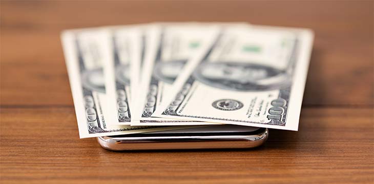 Bunch of dollars flat lying on modern smartphone