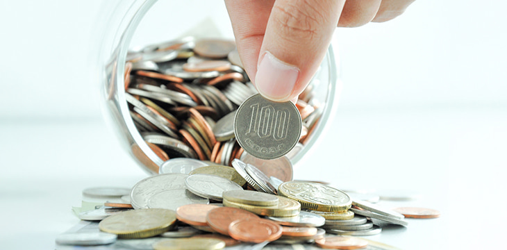 Hand picking up 100 Japanese Yen coin