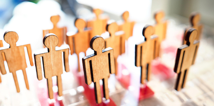 Little wooden toy people figures stand in row