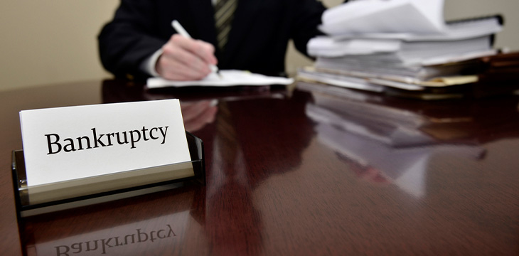 bankruptcy sign with a man signing papers in the background