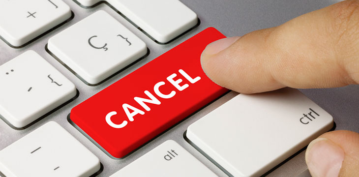 CANCEL Written on Red Key of Metallic Keyboard with finger pressing down on the key