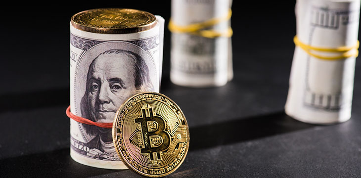 Close-up view of rolled dollar banknotes and bitcoins on black coloured surface