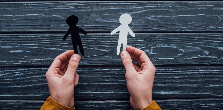 man holding black and white human figures with wooden backgroound