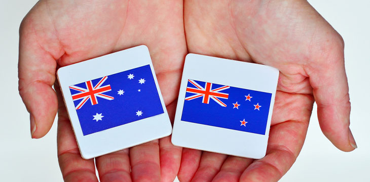 two hands holds the national flags of Australia and New Zealand