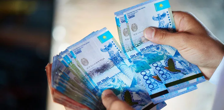 close up image of hands of businessman holding Kazakh money