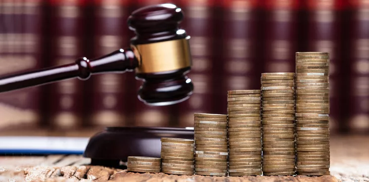 Closeup Of Mallet Being Hit On Stacked Coins At Table In Courtroom