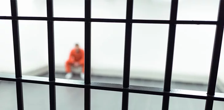 Prisoner behind bars sitting on the floor