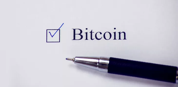 Checklist box with Bitcoin word on white paper with a pen.