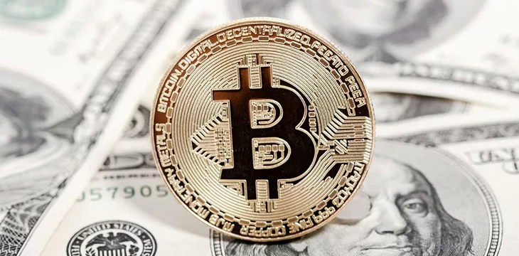 Golden bitcoin coin on dollars