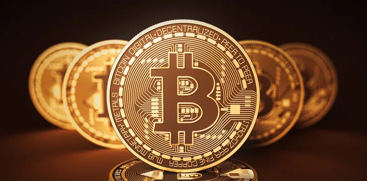 gold bitcoins in a dramatic gradient brown background