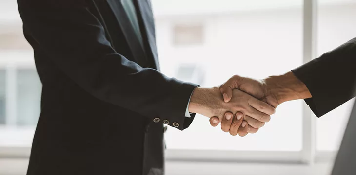 Two businessmen are agreeing on business together and shaking hands after a successful negotiation