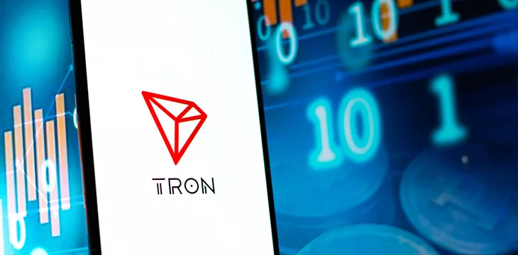 TRON logo on phone screen with stocks background