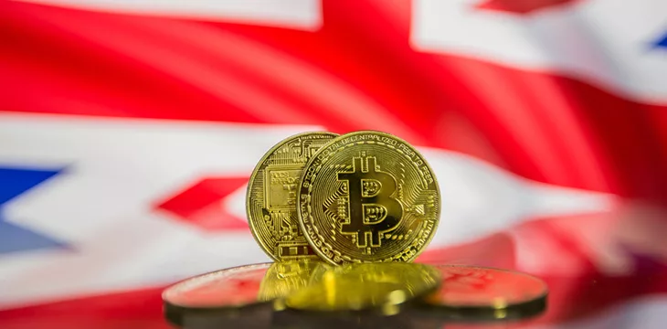 gold bitcoins and defocused flag of United Kingdom