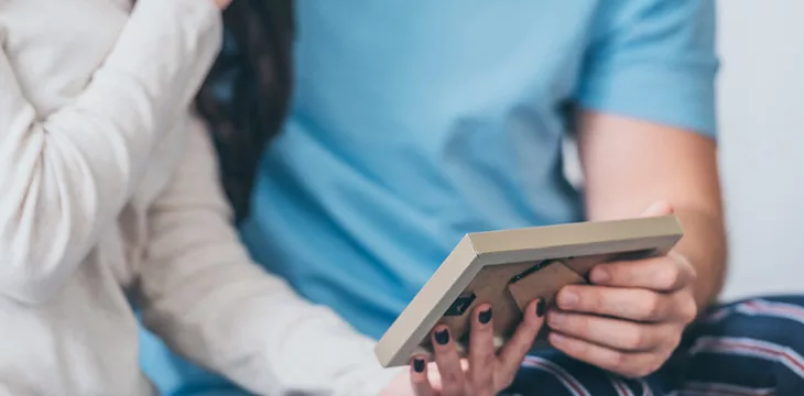 Cropped view of couple holding picture frame