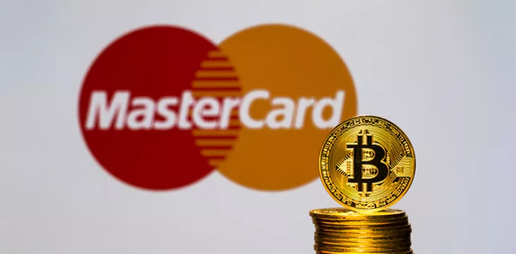 Gold Bitcoin coins with the MasterCard logo on background screen