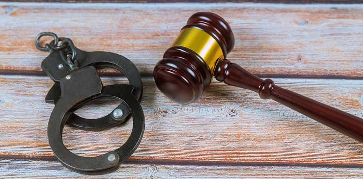 Judge gavel and handcuffs on a wooden table