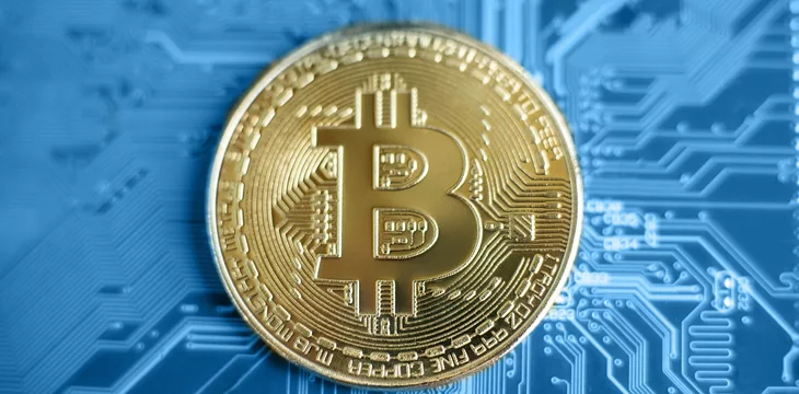 close up image of bitcoin placed on blue circuit board