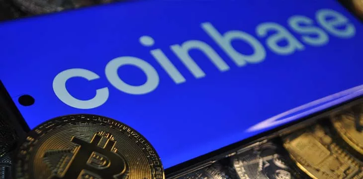 Coinbase logo on a mobile phone with BTC coins