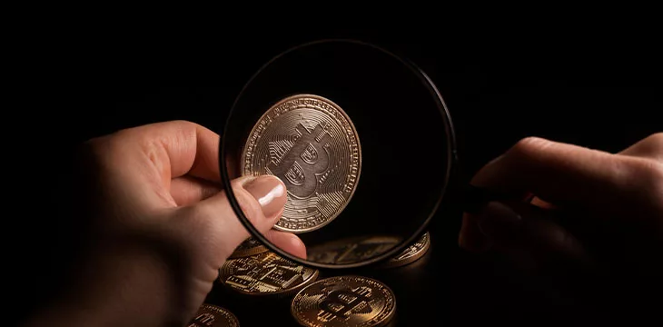 Person holding magnifying glass and looking through it on new digital asset