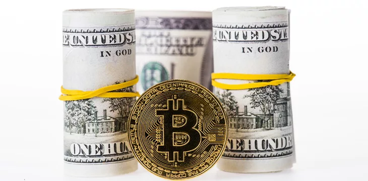 Close-up view of rolled dollar banknotes and Bitcoin isolated on white