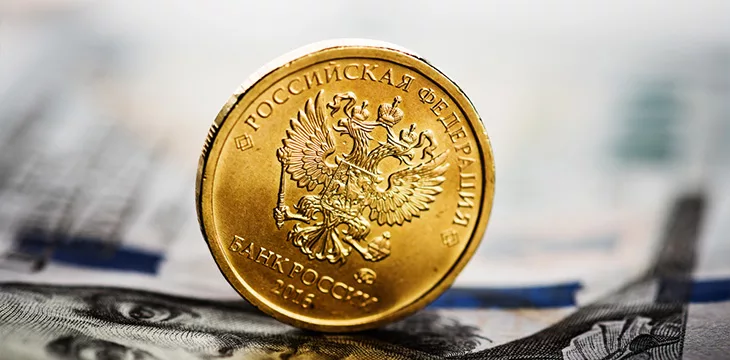 Russian ruble coin on banknotes of U.S. dollars