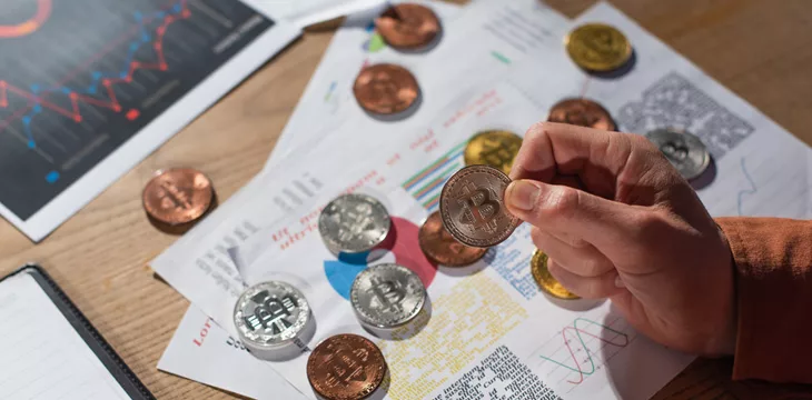 Partial view of man holding digital asset near documents with business analytics on office desk